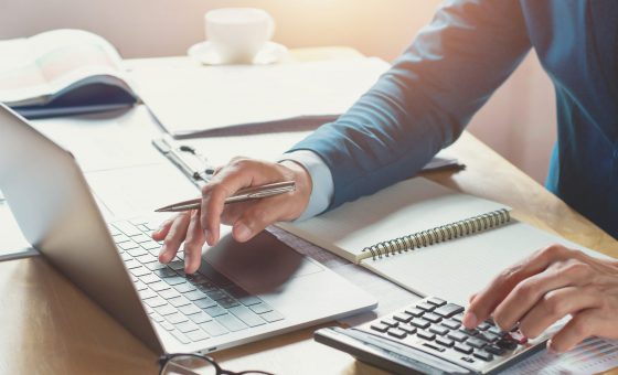 Un homme d'affaires travaillant dans un bureau avec une calculatrice et un ordinateur portable. Concept de finance et comptabilité